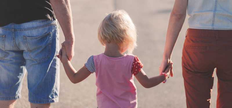 a child holds the hands of two parents with joint custody